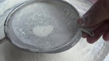 Çiftçinin eli un temizlemek için sepeti kullanıyor.