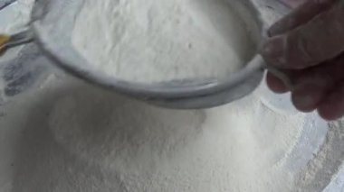 Çiftçinin eli un temizlemek için sepeti kullanıyor.