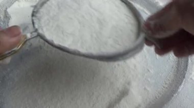 Çiftçinin eli un temizlemek için sepeti kullanıyor.