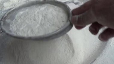 Çiftçinin eli un temizlemek için sepeti kullanıyor.