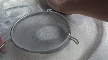 Çiftçinin eli un temizlemek için sepeti kullanıyor.