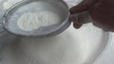 Çiftçinin eli un temizlemek için sepeti kullanıyor.