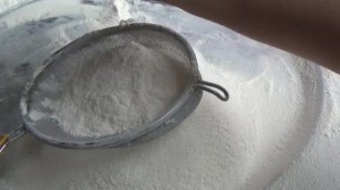 Çiftçinin eli un temizlemek için sepeti kullanıyor.