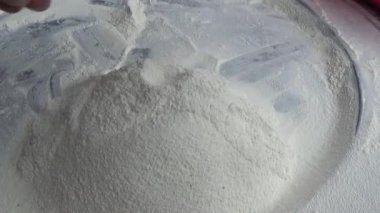 Çiftçinin eli un temizlemek için sepeti kullanıyor.