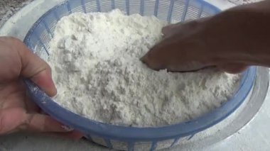 Çiftçinin eli un temizlemek için sepeti kullanıyor.