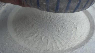 Çiftçinin eli un temizlemek için sepeti kullanıyor.