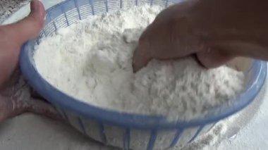 Çiftçinin eli un temizlemek için sepeti kullanıyor.