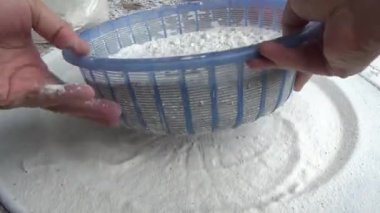 Çiftçinin eli un temizlemek için sepeti kullanıyor.