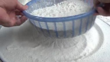 Çiftçinin eli un temizlemek için sepeti kullanıyor.