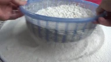 Çiftçinin eli un temizlemek için sepeti kullanıyor.