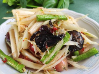 Beyaz tabakta baharatlı papaya salatası (Som Tum) Tayland geleneksel yemeği. Sığ alan derinliği.