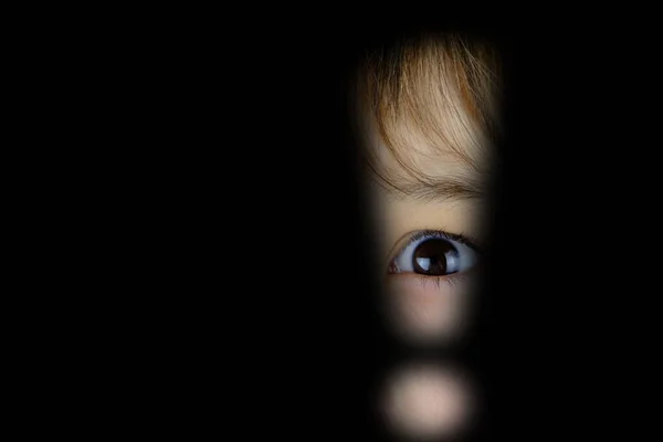part of child\'s face, eye looking through hole exclamation point in dark, stress problems, difficult childhood, victim of domestic violence, psychological difficulties, concept of seeing scary