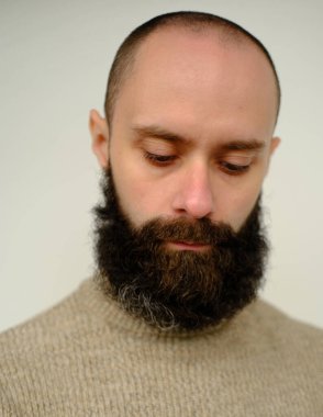 Üzgün, uykulu, genç, dalgın sakallı ve bıyıklı adam, 30 yıllık bej renkli kazaklı tatmin olmuş adam aşağıya bakıyor, insan sağlığı kavramı, hayatın anlamını yansıtıyor.