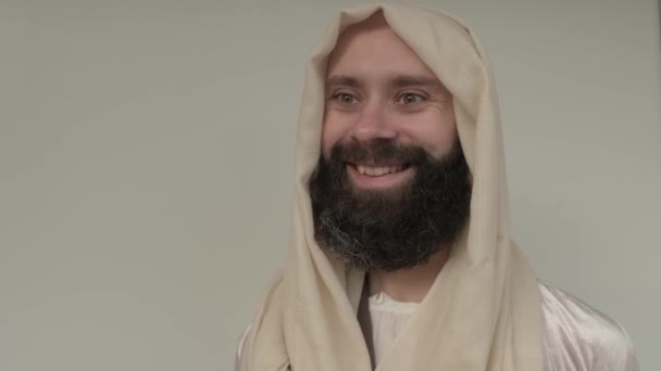 圣经的场景 耶稣基督 年轻的苦思冥想的胡子男人 30岁的小伙子穿着浅色的衣服 米色的斗篷代表了救世主的形象 新旧约圣经的概念 — 图库视频影像