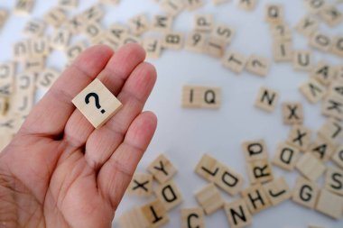 Kadın bilim adamının elinde soru işareti, kelime IQ 'lu tahta kareler, tahta arka planda zeka seviyesi, başarıyı ifade eden nicel gösterge, zihin seviyesi kavramı...