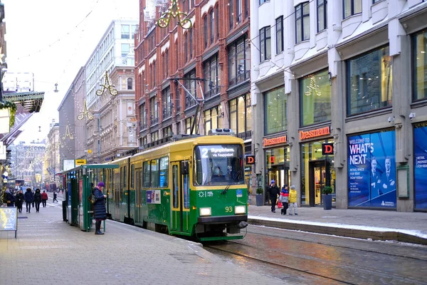 stock image people walking along winter street Helsinki city, modern green tram rides on rails, concept holiday shopping, passenger traffic, enjoying Christmas festive atmosphere, Helsinki, Finland - January 2022