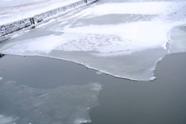 Nehirde, gölde, şehir rezervuarında buz, karanlık suda yüzer, geçilmesi tehlikeli buz blokları, donma sırasında boğulma konsepti, buzun içine düşme, kış doğasının mevsimsel fenomeni