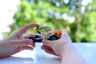 child's fingers move transformer car, manipulator, assembled from designer parts, green background, concept fine motor skills, creativity, children's entertainment, invention, Frankfurt - June 2022