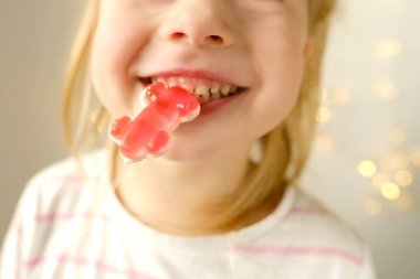 portrait of small child, blonde girl 3 years old wants to eat gelatinous sweets, gummy bear, kid has a good appetite, happy childhood, balanced diet, sweet life, unhealthy food, halal food