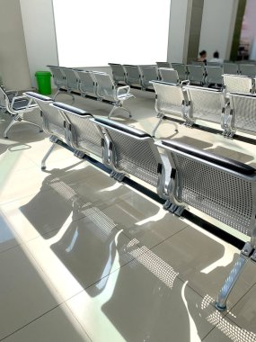 comfortable metal rows of seats in bright airport lounge, Airport waiting room with empty blank billboard, concept passenger traffic, delay, flight cancellation, arrival time, international voyage