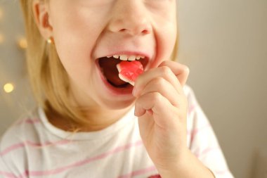 portrait of small child, blonde girl 3 years old wants to eat gelatinous sweets, gummy bear, kid has a good appetite, happy childhood, balanced diet, sweet life, unhealthy food, halal food