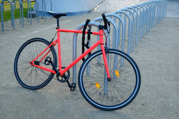 bright red, scarlet classic bicycle in urban landscape sunset parked in bike parking lot, punctured wheel problem, repair of vehicles in city, public bike rental, bike saddle sharing, property theft