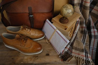 old nostalgic sentimental things, letters, stack of books, globe, shoes, vintage leather military satchel on table, checkered grandmother's plaid, family tree, home archive, memory of ancestors
