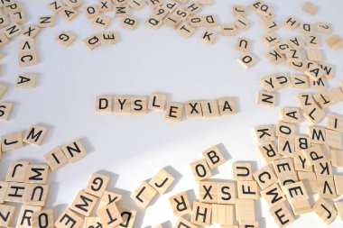 closeup wooden alphabet blocks, DYSLEXIA word on white background, dyslexia awareness, learning disability, help with reading, learning difficulties, human brain development, literacy problems concept