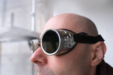 close up part male face, eyes of young pensive man 30 years old in black glasses, steampunk style, concept post-apocalyptic reality, vision examination, treatment of ophthalmic diseases