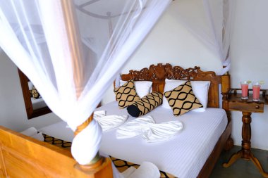 Sivrisinek ağlı rahat yatak odası, beyaz örtü örtüsü, apartman odasındaki ahşap yatak odası, dört direkli yatağın yanındaki otel, sivrisinek ağlı rahat yatak odası, tropikal bölgede tatilin tadını çıkarıyor.
