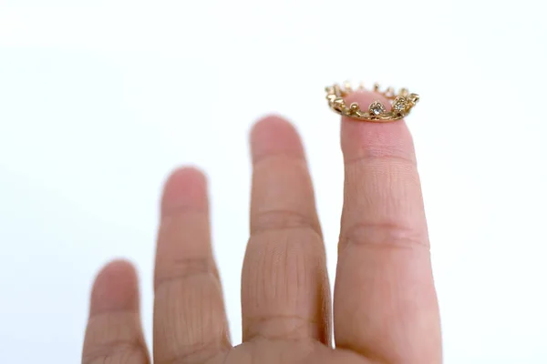 close up miniature metal silver crown, diadem on finger female hand, concept supreme power, underestimation, triumph, symbol of superiority, supreme dignity, level in hierarchy, leadership in business