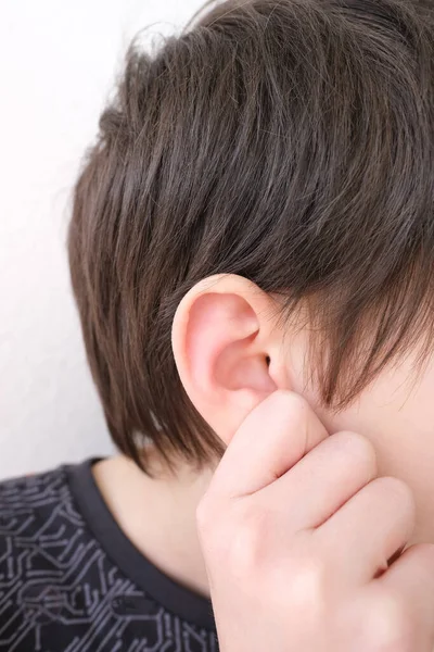 part of child\'s face in profile, boy of 10 years old touches sore ear, concept of hearing organs health, happy childhood, prevention of otitis media and hearing loss, World Hearing Day