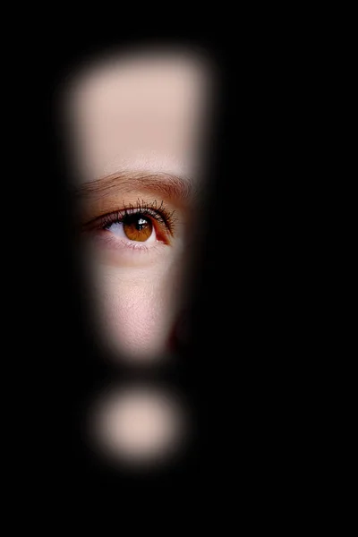 close-up of part of face, serious eye looking through hole exclamation point in dark, concept of seeing scary, stress problems, domestic violence, difficult childhood, psychological difficulties