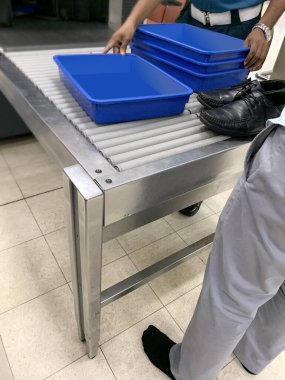 Yolcu ayakkabılarını taşıyıcıya koydu, havaalanı personeli cihazlar, çantalar, kutular için plastik konteynırları X-ray havaalanı kontrol noktasına, hava yolculuğu için gerekli güvenlik önlemlerini aldı.