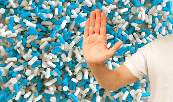 male hand hand, stop gesture, blue vitamins, capsule, pills, medicinal background, concept development medicine and pharmacology, health, humanization intensive care, drug addiction problems, overdose