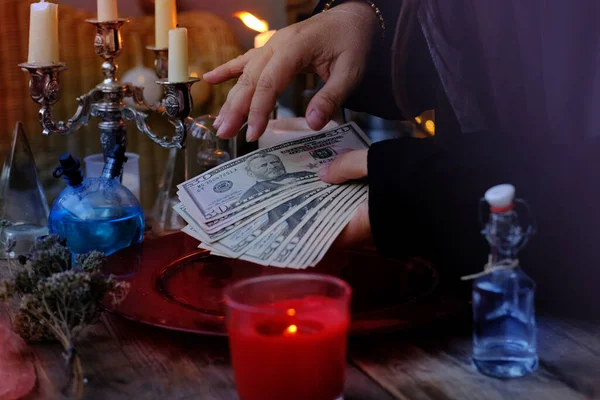 Librate with money, female hands of psychic doing witchcraft passes with dollars, esoteric Oracle performs ritual of removing spell of black magic, esoteric business, magic to increase income