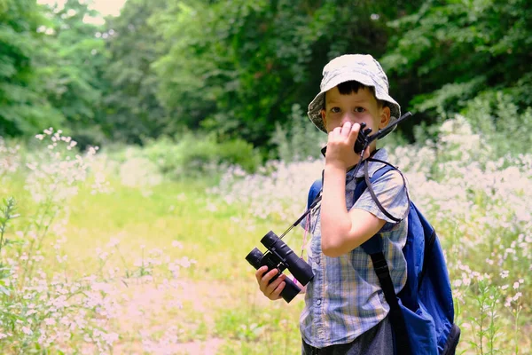 8年の子供 パナマの帽子の少年 手に双眼鏡でシャツを再生森の中に立つ ポータブルラジオで話す オリエンテーリング 野生での生存のハイキングの概念 — ストック写真