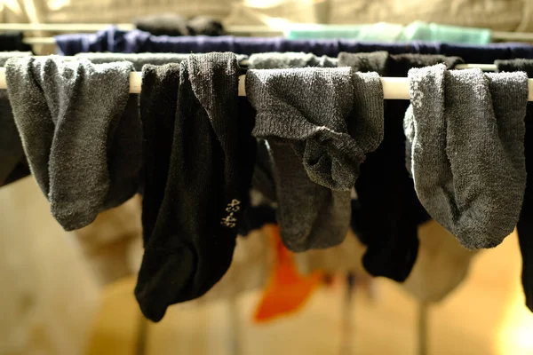 close-up of wet dark men\'s socks, laundry hanging and drying on wire room dryer, home chores concept, gentle hand washing of lacy underwear, homework, selective focus at shallow depth of field