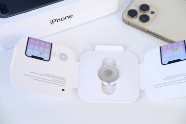 Apple Airtag, elektronik takip cihazlı beyaz kutu, takip cihazı Bluetooth üzerinden güvenli sinyal yayıyor, yakındaki cihazlar tarafından algılanıyor, coğrafi konum, çocuk güvenliği kavramı, araba hırsızlığı önleyici cihaz