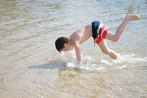 happy cool funky child, healthy boy 9-10 years old fun plays in water, sea, ocean, river, doing somersaults, frolic, playing in water, splashing in splashes, concept learning swimming skills