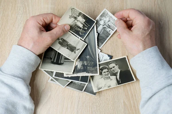 stock image an elderly man looks through his old photographs of 1950-1955, the concept of nostalgia and memories of youth, childhood, remembering his life, relatives, family connection of generations