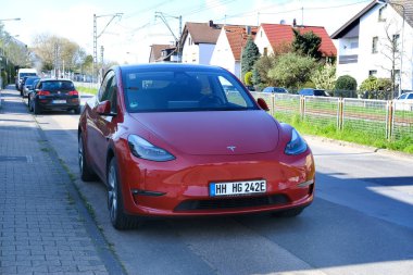 Sokakta kırmızı renkli araba, kablo ile elektrik yükleme, Avrupa şehrinde elektrikli araç, enerji silindirik akülatörler, alternatif enerji gelişimi, teknoloji ve yenilik