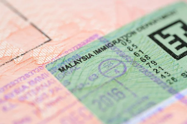 close-up part of page of document, foreign passport for travel with Malaysia visa, tourist visa stamp with hologram with shallow depth of field, passport control at border, travel in Southeast Asia