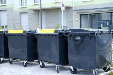 Almanya 'da sıra sıra siyah plastik çöp konteyneri, belirlenen yerde çöp toplama, çevre konsepti, atık ayırma farklı türde belediye atığı toplanması ve ayrı ayrı geri dönüştürülmesi anlamına geliyor