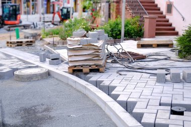 gray paving blocks on ballast, sewer well, construction site of pavement modern granite cobblestone road in city center, roadworks stonework at pedestrian area, concept installation, renovation