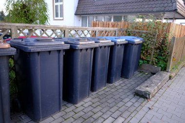 Almanya 'da sıra sıra siyah plastik çöp konteyneri, belirlenen yerde çöp toplama, çevre konsepti, atık ayırma farklı türde belediye atığı toplanması ve ayrı ayrı geri dönüştürülmesi anlamına geliyor