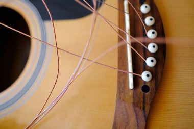 Enstrümanın yakın plan ahşap parçası, akustik gitarın tellerini değiştirmek, serbestçe asılı duran teller, gitar akordu, müzik enstrümanları çalmak için enerjik performanstan koparılmış tellerin değiştirilmesi.