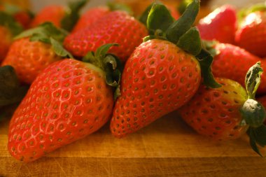 İştah açıcı kırmızı çilekler, Fragaria, ahşap tahtada, aydınlatılmış vatozlar güneş, taze vitamin sulu meyve, zengin hasat bahçıvanlığı, vejetaryen, vitamin, sağlıklı yiyecekler, sağlıklı beslenme kavramı.