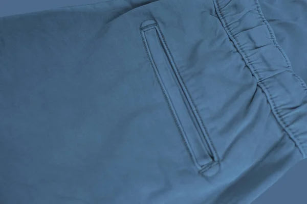 close-up of texture of blue cotton trousers, pants with welt pockets, ankle cuffs, drawstring at the waist, concept of check quality, fashionable clothe