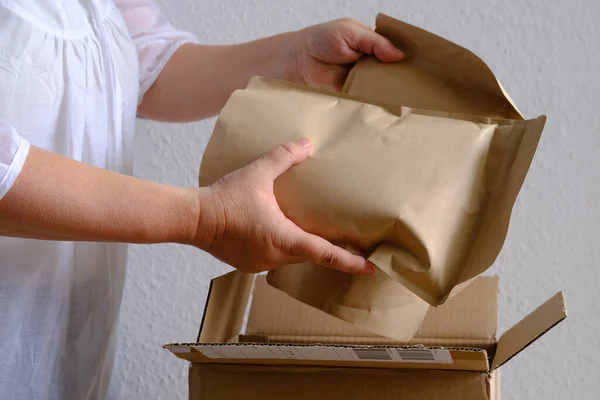 closeup of female hands take out package from open cardboard box, bundle collagen, postal box with wrapping paper, parcel, delivery of ordered goods, online shopping, timely delivery to customers